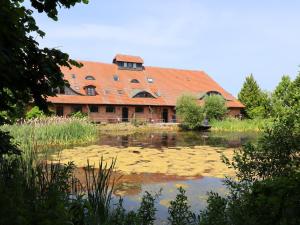 a building with an orange roof next to a pond at Buschenhagen Rustic Getaway in Buschenhagen