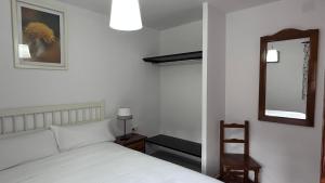 Un dormitorio con una cama blanca y un espejo. en Posada El Rincón de Valverde, en Valverde de los Arroyos