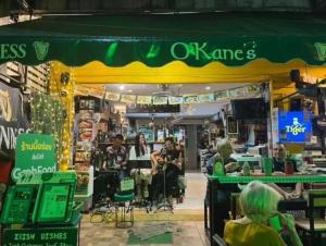 a group of people sitting in front of a store at O'Kane's Pub and Hostel in Chiang Rai