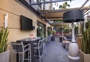 a patio with tables and chairs and a tv on the wall at Hilton Garden Inn Los Angeles / Hollywood in Los Angeles