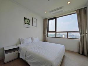 a bedroom with a white bed and a large window at Starlake Daewoo Deluxe Apartment Managed by Anstay in Hanoi