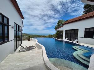 a swimming pool in front of a house at 3 Bedroom Beautiful and Private Sunset Sea Views Villa Mango SDV153-By Samui Dream Villas in Bophut 
