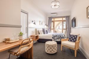 a bedroom with a bed and a desk and chair at Bermagui Beach Hotel in Bermagui +26 photos