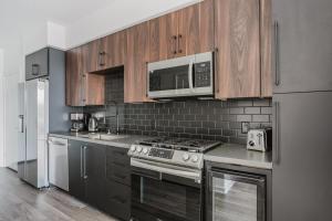 a kitchen with stainless steel appliances and wooden cabinets at Blueground Long Beach pool gym near bars LAX-1260 in Los Angeles