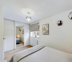 a white bedroom with a bed and a mirror at Modern 2 bed city apartment with private parking in Swansea