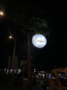 a sign hanging from a tree at night at Manawari Beach Resort in Caliclic
