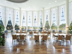 a restaurant with tables and chairs and large windows at Grand Mercure Awaji Island Resort & Spa in Minamiawaji