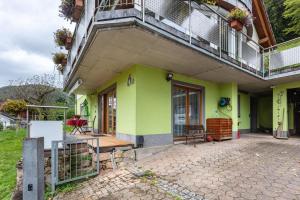 a green building with a balcony and a patio at Ferienwohnung Sonnenberg in Degerfelden