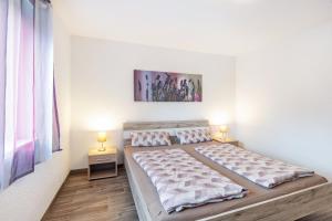 DegerfeldenにあるFerienwohnung Sonnenbergの白いベッドルーム(ベッド2台、ランプ2つ付)