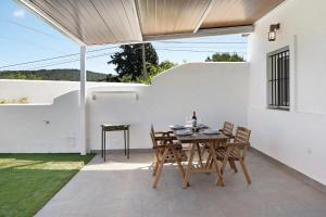 a table and chairs on a patio with a white wall at Viviendas Turísticas El Moral in Vejer de la Frontera
