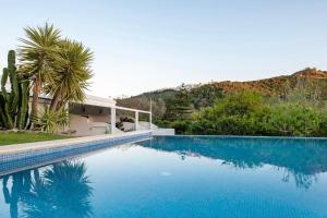 a large blue swimming pool in front of a house at Viviendas Turísticas El Moral in Vejer de la Frontera