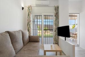 a living room with a couch and a tv at Viviendas Turísticas El Moral in Vejer de la Frontera