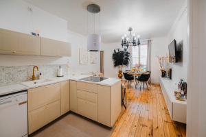 a kitchen with white cabinets and a wooden floor at RoomChic - Les Ambassadeurs in Vichy