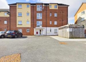 a parking lot in front of a large brick building at Modern 2 bed city apartment with private parking in Swansea