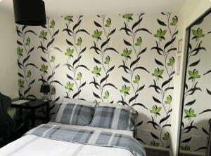 a bedroom with a bed with a wall with green flowers at Townhead Road in Inverurie