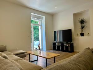 Una sala de estar con un sofá, una mesa y un televisor. en Charmant quadruplex au cœur de la Vallée, en La Broque
