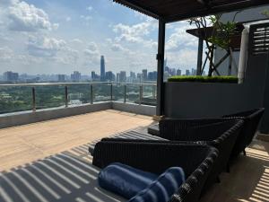 einen Balkon mit 2 Stühlen und Stadtblick in der Unterkunft KL City Nue Suites Entire Condo 2R2B 3 plus 1 guests in Kuala Lumpur