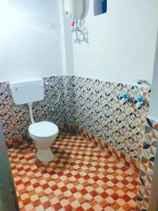 une salle de bain avec toilettes et un mur carrelé dans l'établissement Chamtaburu Eco Resort, à Bāghmundi