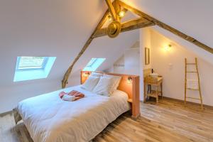 a bedroom with a bed with white sheets and a ladder at La Bergerie des 2 Tilleuls - Maison avec jacuzzi in Marcy-sous-Marle