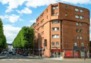 un edificio de ladrillo rojo en una calle de la ciudad en B&B HOTEL Lille Roubaix Centre Grand-Place, en Roubaix