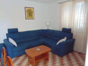 a blue couch in a living room with a table at Apartment Fran in Postira