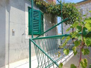 a green railing next to a window with a green shutter at Apartment Fran in Postira