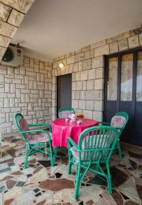 a table with green chairs and a pink tablecloth at Apartments Juri in Sućuraj