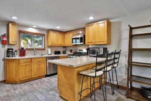 a kitchen with wooden cabinets and a counter with bar stools at West Park Chalet - Large Vermont Ski Home - Great for Groups! Hot tub, games, ski rental ticket deals! in Killington