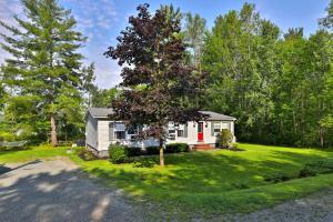 a small white house in the middle of a yard at The Bomoseen Bungalow - Vermont Lake House Close to Ski Resorts! Private dock, ski rental ticket deals in Bomoseen
