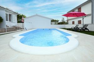 a large pool in a backyard with an umbrella at Apartment Mihovilovic in Slatine