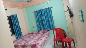 a bedroom with a bed and two red chairs at HOTEL AMARNATH Bakkhali in Bakkhali