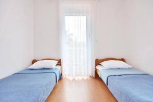 two beds sitting in a room with a window at Apartment Toma in Omiš