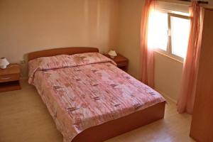 a bedroom with a bed with a pink comforter and a window at Apartment Dita in Nin