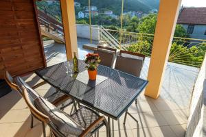 a glass table with a vase of flowers on a balcony at Apartments Vesna in Luka