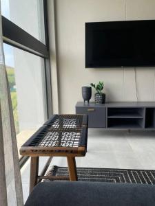 - un salon avec un banc et une télévision à écran plat dans l'établissement Zimbali Boulevard Suites 203 Beautiful bliss, à Ballito