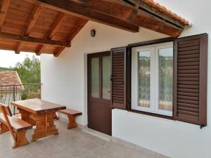 a patio with a wooden table and a bench at Apartments Branko in Podstražje +3 photos