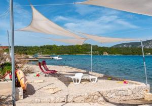 a beach with a table and chairs and an umbrella at Apartments Zeljko in Račišće