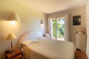 a bedroom with a white bed and a window at A Cala d Oro et plage privée pour 8 in Porto-Vecchio