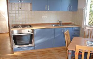 a kitchen with blue cabinets and a stove and a table at Apartments Dijana in Sveta Nedelja