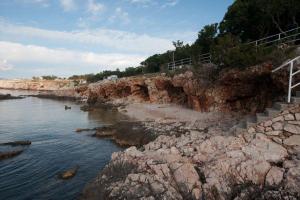 een strand met rotsen en een brug over het water bij Apartments Luka in Novi Vinodolski
