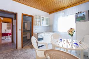 a kitchen with a white table and chairs and a table and a kitchen at Apartments Ante in Smokvica