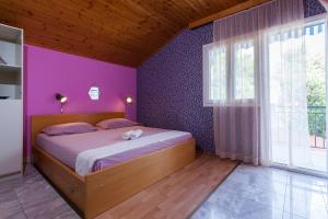 a bedroom with a bed with a purple wall at Apartments Ante in Smokvica