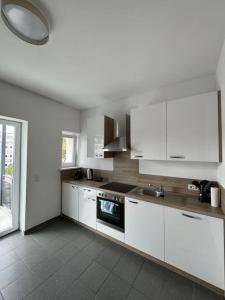 une cuisine avec des armoires blanches et un évier dans l'établissement Sonnige Wohnung mit Balkon im Herzen von Bayreuth, à Bayreuth