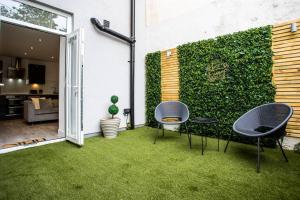 a garden with two chairs and a green wall at The Cove - Roker Sea Front - Vacant Nests in Sunderland