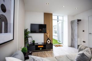 a living room with a couch and a flat screen tv at The Cove - Roker Sea Front - Vacant Nests in Sunderland