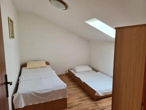 um pequeno quarto com 2 camas e uma clarabóia em Apartments Stosa em Nin