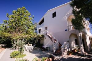 a white building with stairs and a table and chairs at Apartment Zdrave in Vlašići
