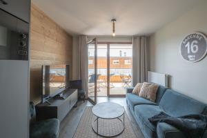 ein Wohnzimmer mit einer Couch, einem Fernseher und einem Tisch in der Unterkunft Alpe d'Huez Houses - Chez Stef - Alpe d'Huez Houses - 45m2 de confort plein sud in L'Alpe-d'Huez