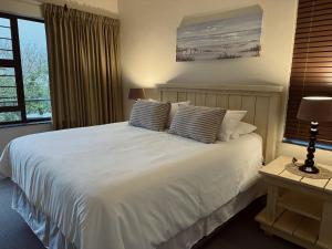a bedroom with a bed with white sheets and a window at Rockshore at Seaverge in Port Edward