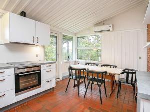 Una cocina con gabinetes blancos y una mesa y sillas. en 6 person holiday home in Gilleleje, en Gilleleje